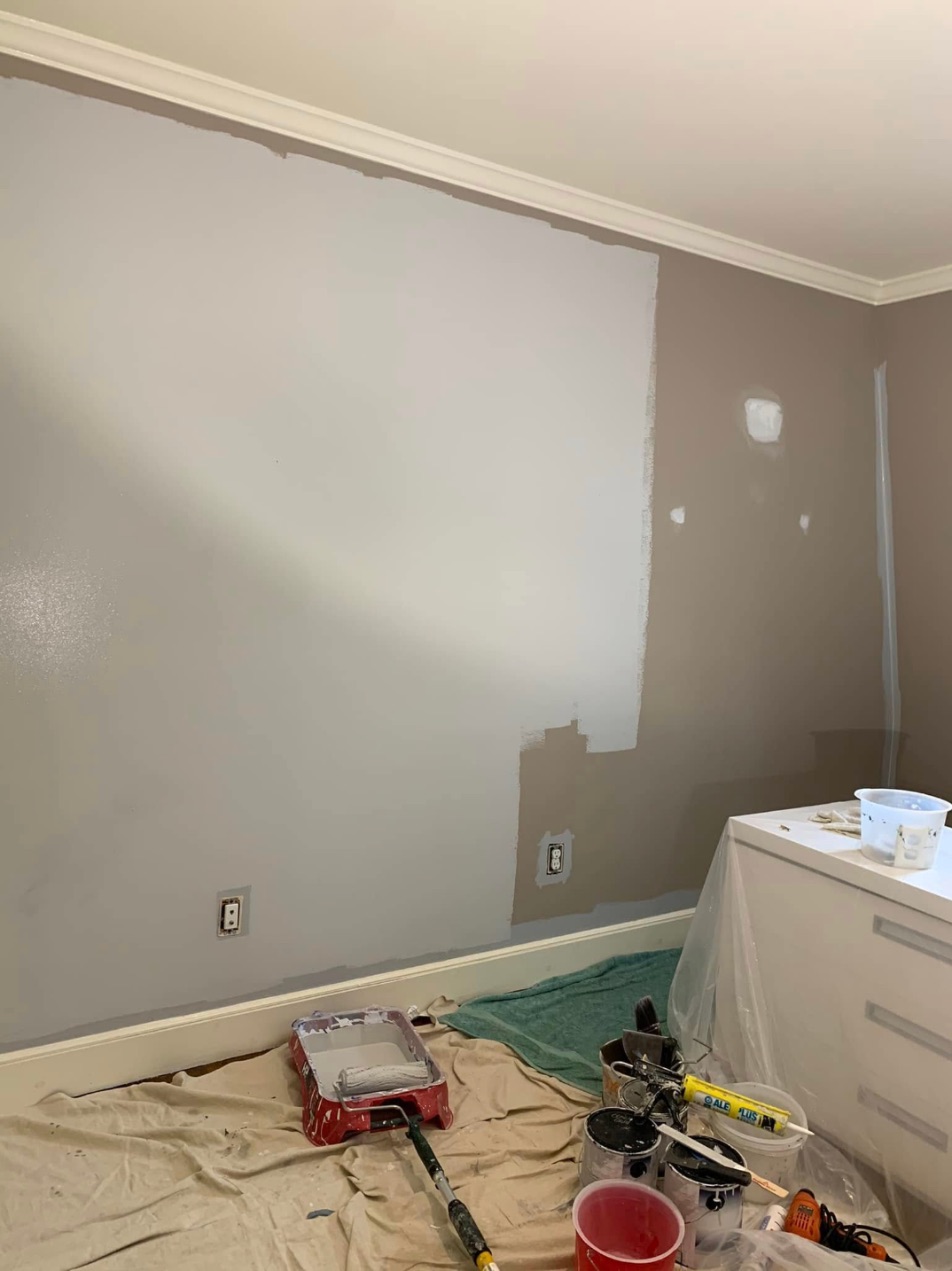 Wall halfway painted in a fresh light gray, showing the new color over the old