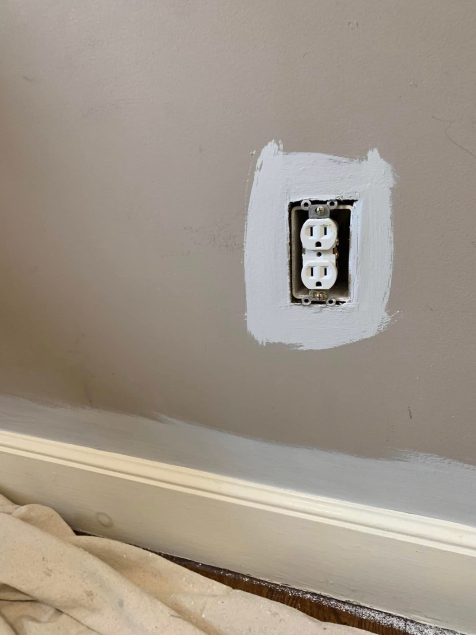 Repair around an outlet primed before paint, floor covered with drop cloth